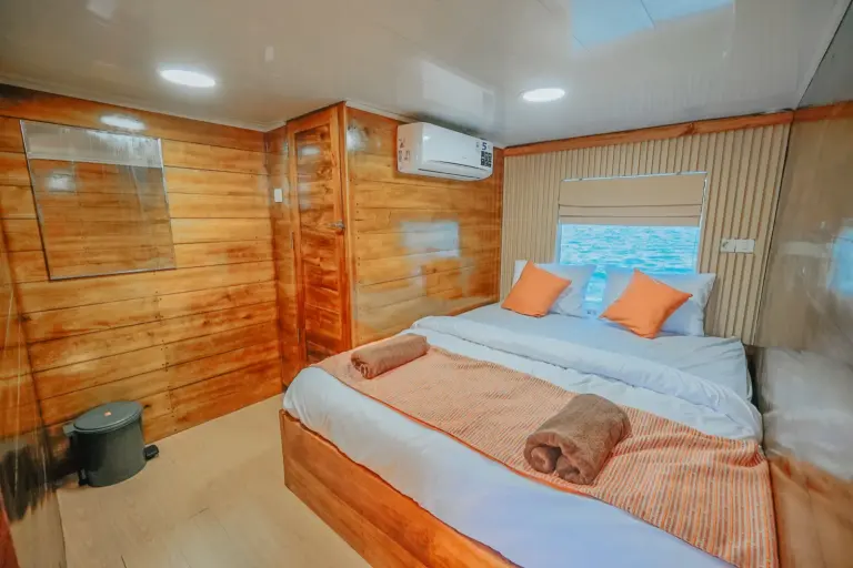 Kabin Deluxe Segara di upper deck, ranjang queen dan dinding kayu